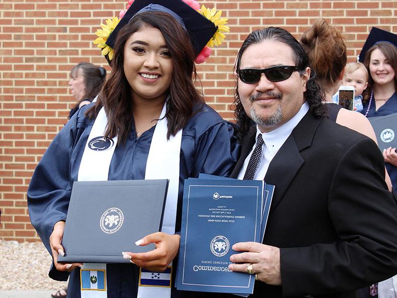 Young female graduate poses with her father at graduation